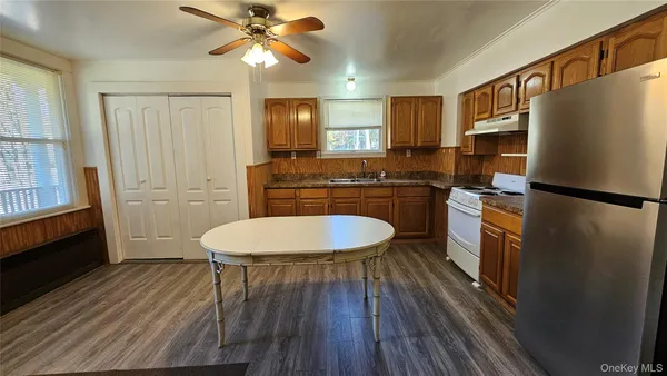 a kitchen with a refrigerator a sink dishwasher a stove and white countertops with wooden floor