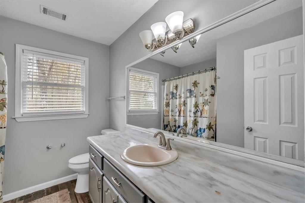 3410 Pilot Road Covington, GA 30014 - Photo 26 of 66 a bathroom with a granite countertop double vanity sink a toilet and a window