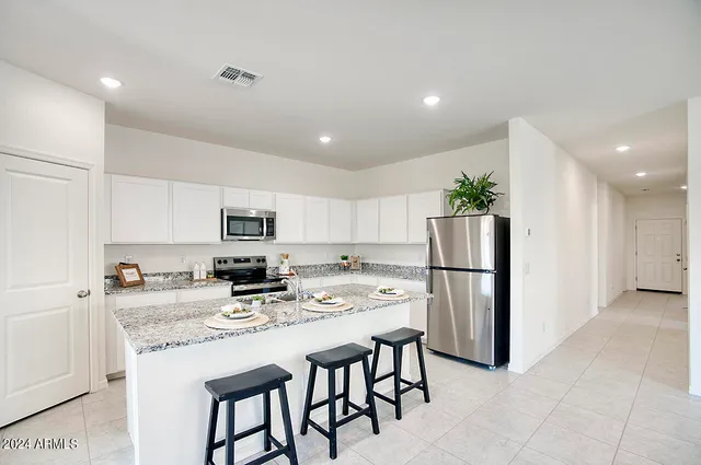 a kitchen with a refrigerator a stove a sink and white cabinets with wooden floor