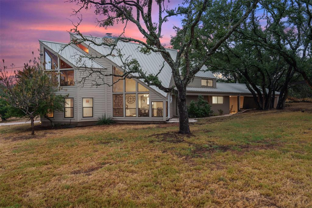 Back of property at dusk with a lawn, a chimney, and a metal roof