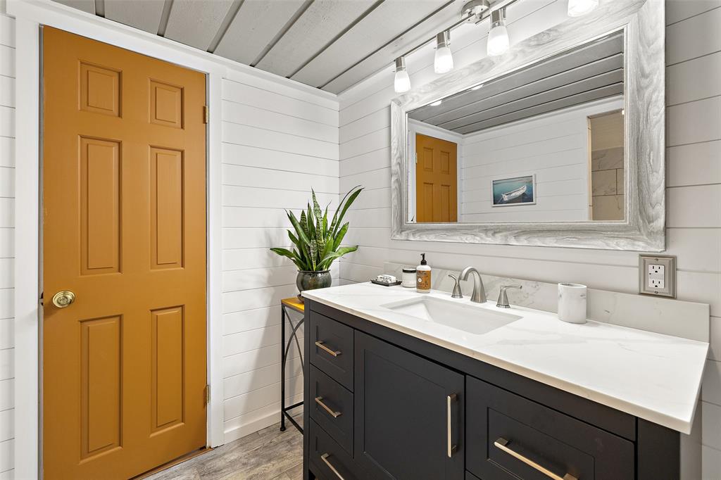 318 Coventry Road Spicewood, TX 78669 - Photo 14 of 38 Bathroom featuring vanity, light wood-style floors, and wooden walls