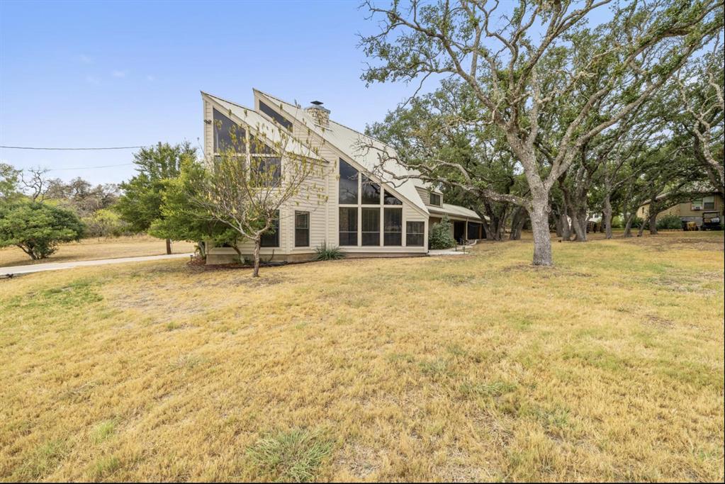 318 Coventry Road Spicewood, TX 78669 - Photo 15 of 38 Back of house with a sunroom, a lawn, and a chimney