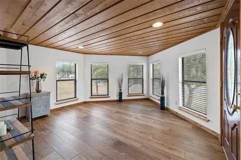 a view of empty room with wooden floor and floor to ceiling window