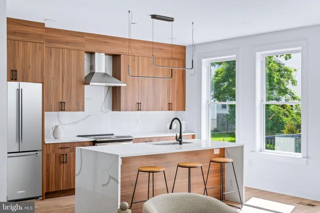 a kitchen with stainless steel appliances granite countertop a sink a window and white cabinets