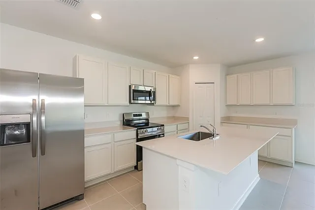 a kitchen with stainless steel appliances a white stove top oven a sink a refrigerator and white cabinets
