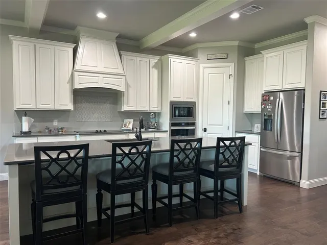 a kitchen with stainless steel appliances granite countertop a table chairs microwave and refrigerator
