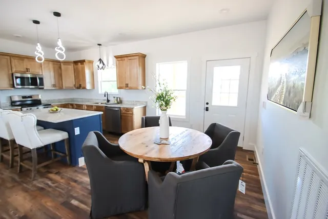 a dining room with wooden floor a chandelier a wooden table and chairs