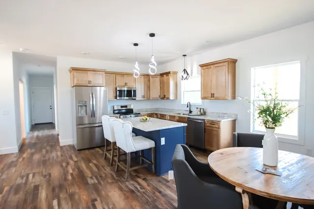 a kitchen with kitchen island granite countertop a sink cabinets and wooden floor