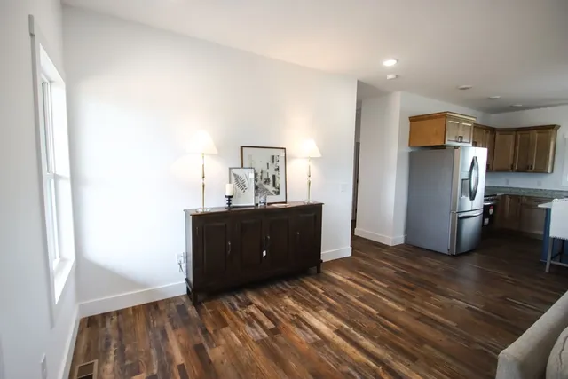 a view of a kitchen with refrigerator and wooden floor