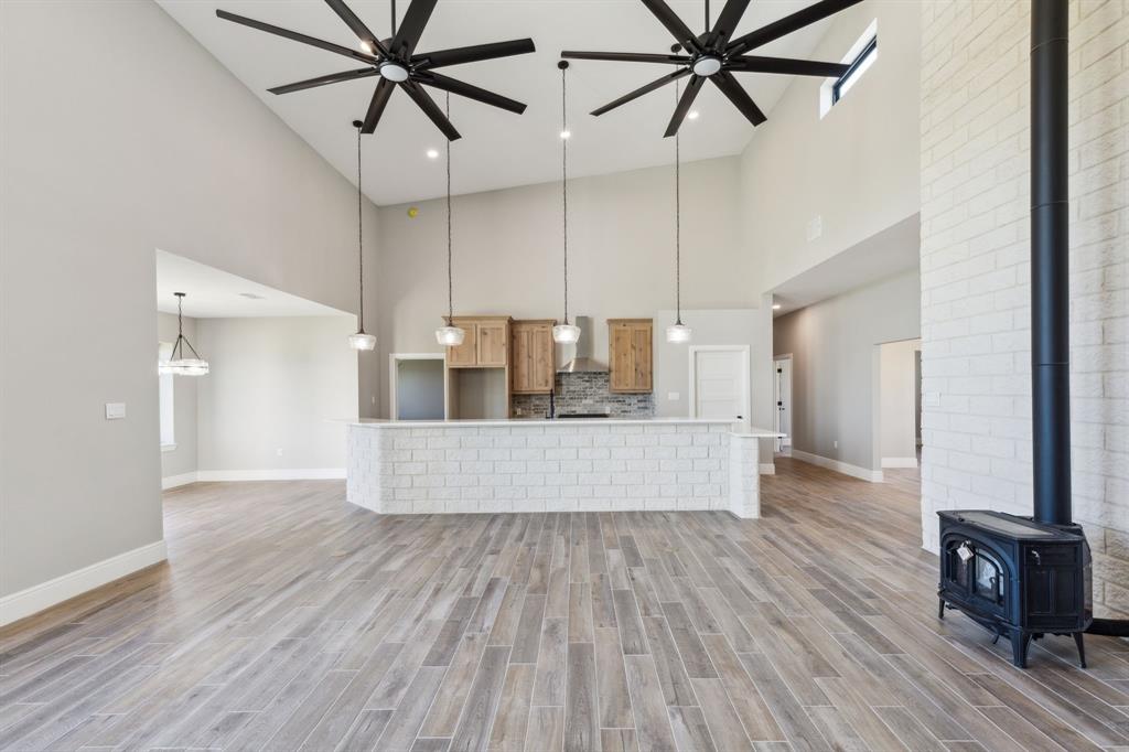 700 Brown Road Palo Pinto, TX 76484 - Photo 11 of 40 Living room with high vaulted ceiling, ceiling fan, baseboards, and a wood stove