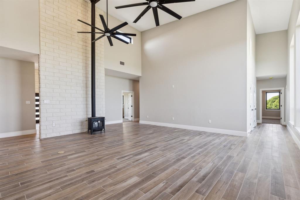 700 Brown Road Palo Pinto, TX 76484 - Photo 14 of 40 Living room featuring baseboards, a wood stove, high vaulted ceiling, electrical outlet in the floor and ceiling fan.
