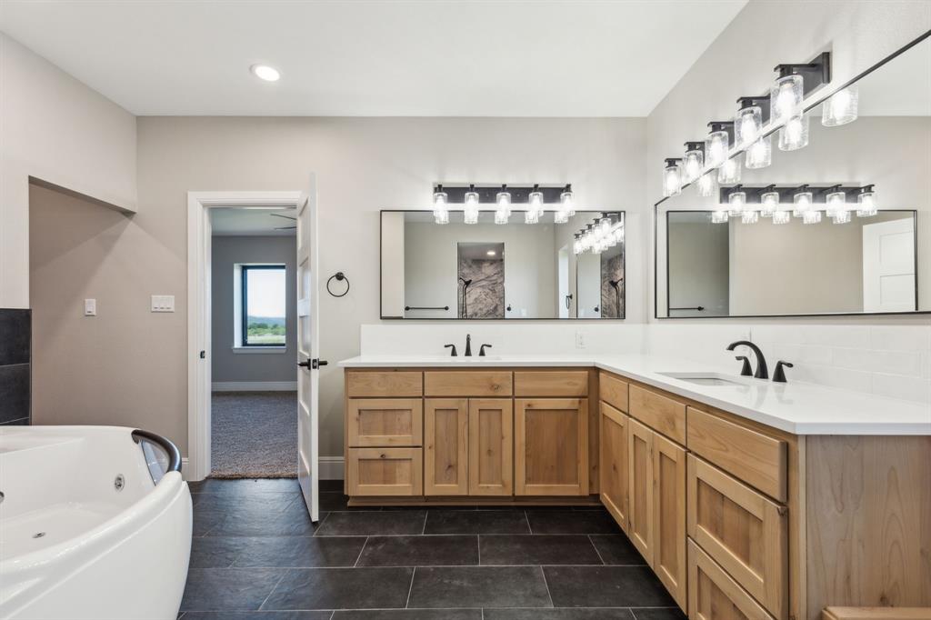 700 Brown Road Palo Pinto, TX 76484 - Photo 21 of 40 Primary bathroom with jetted tub for 2, double sink vanity, and recessed/decorative lighting.