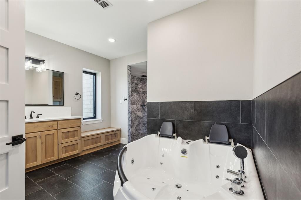 700 Brown Road Palo Pinto, TX 76484 - Photo 22 of 40 Primary bathroom with jetted tub for 2, double sink vanity, and recessed/decorative lighting.