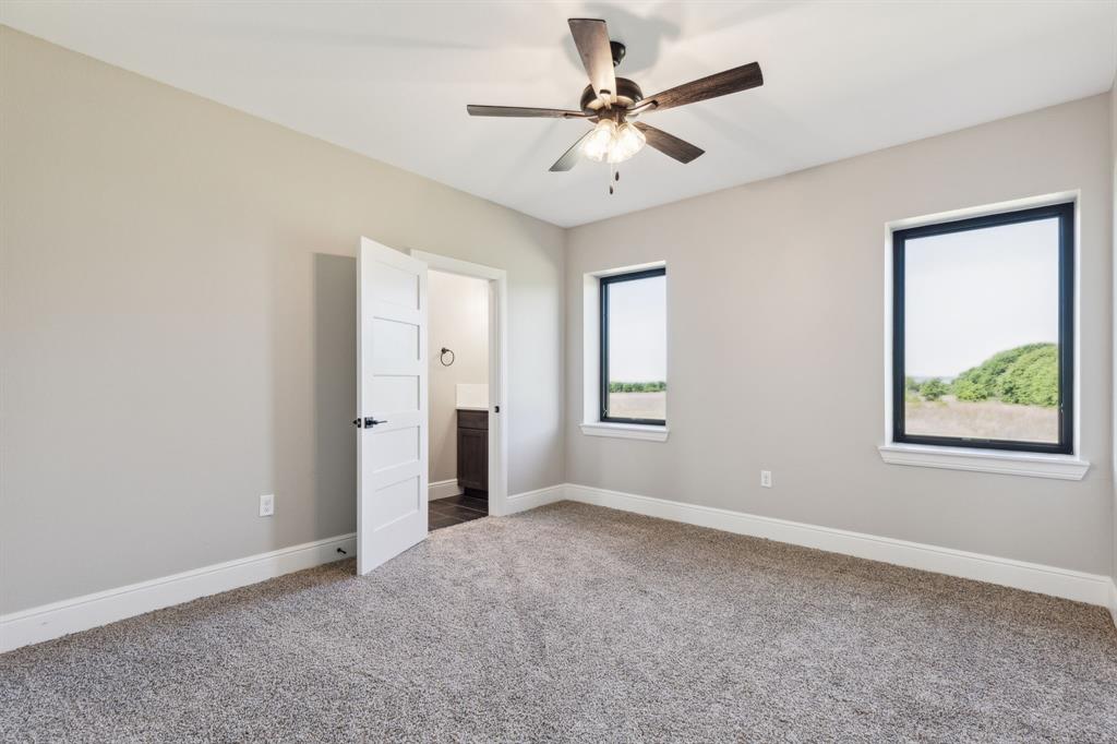 700 Brown Road Palo Pinto, TX 76484 - Photo 28 of 40 Bedroom featuring ensuite bath, baseboards, carpet, and a ceiling fan