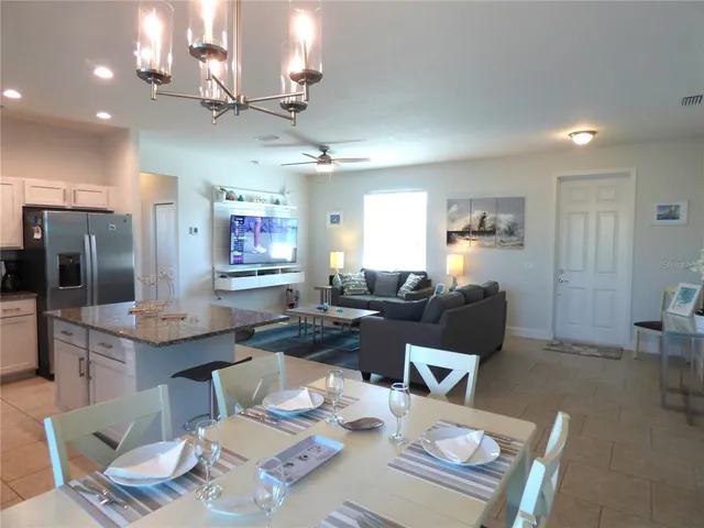 a kitchen with stainless steel appliances kitchen island granite countertop a sink a stove a refrigerator cabinets and chairs