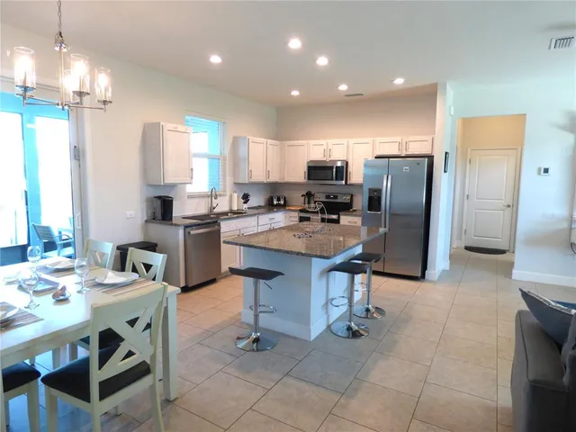 a kitchen with stainless steel appliances granite countertop a sink a stove a refrigerator a counter top space and cabinets