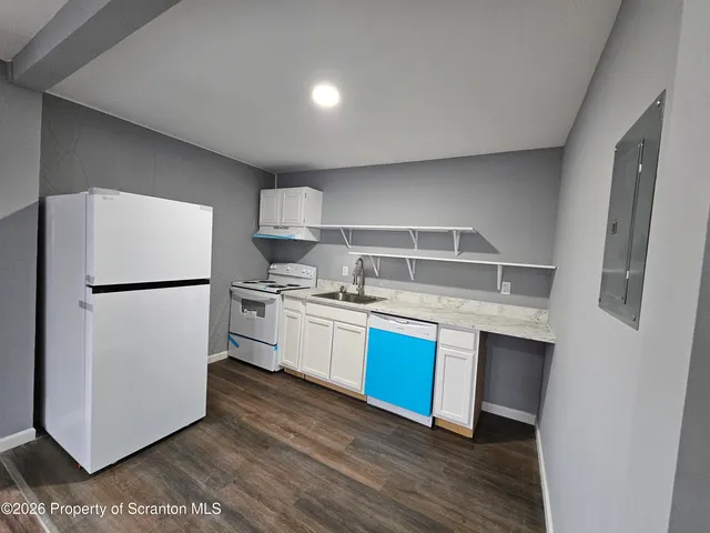 a kitchen with stainless steel appliances white cabinets and wooden floor