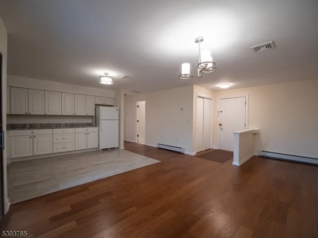 an empty room with wooden floor cabinet and windows