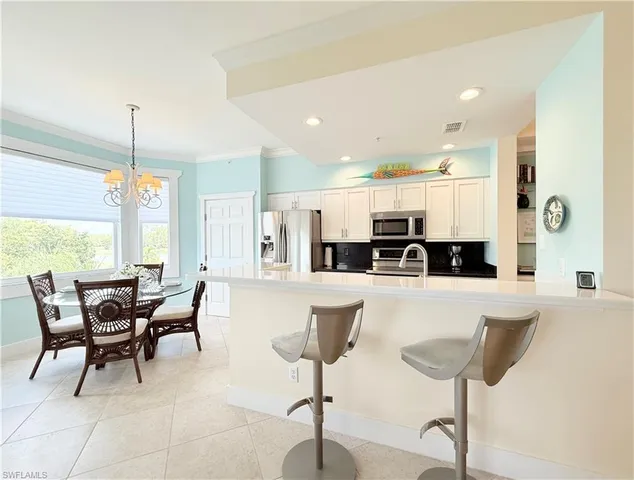 a kitchen with stainless steel appliances kitchen island granite countertop a table and chairs in it