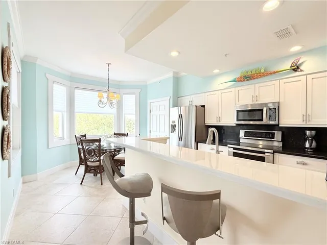 a kitchen with stainless steel appliances kitchen island granite countertop a sink and a refrigerator