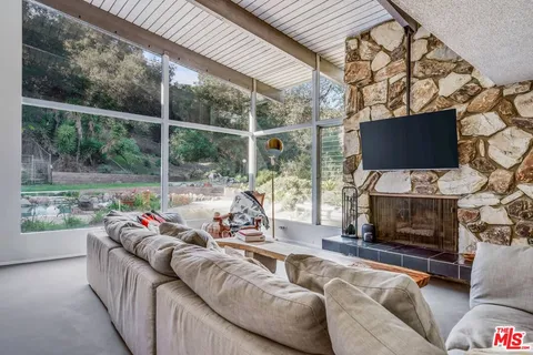 a living room with furniture a flat screen tv and a floor to ceiling window