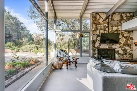 a living room with furniture a flat screen tv and a floor to ceiling window