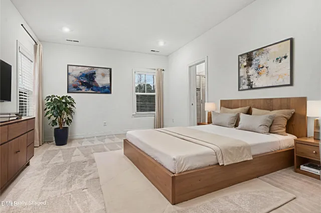 a spacious bedroom with a large bed and a potted plant