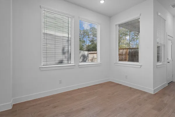 a view of an empty room with wooden floor and windows