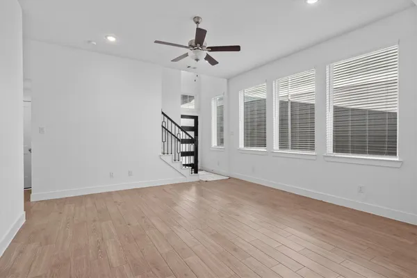a view of an empty room with a window and wooden floor