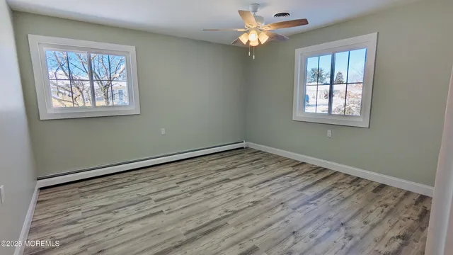 a view of empty room with wooden floor and fan
