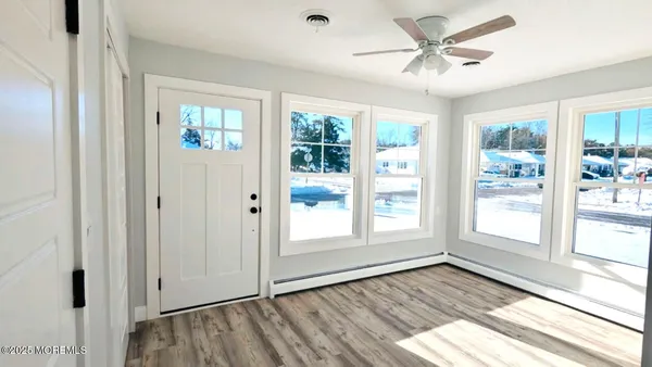 a view of an empty room with a window and wooden floor