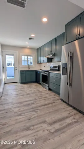 a kitchen with stainless steel appliances kitchen island granite countertop a refrigerator and a sink