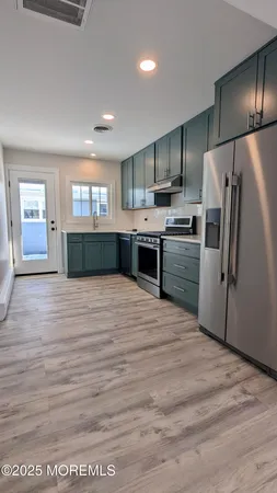 a kitchen with stainless steel appliances kitchen island granite countertop a refrigerator and a sink