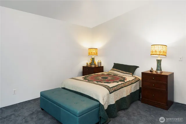 a bedroom with a bed and a lamp on dresser