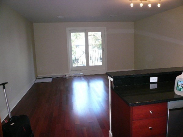 533 Cambridge Street, Unit 212 Boston, MA 02134 - Photo 3 of 7 an empty room with wooden floor and windows
