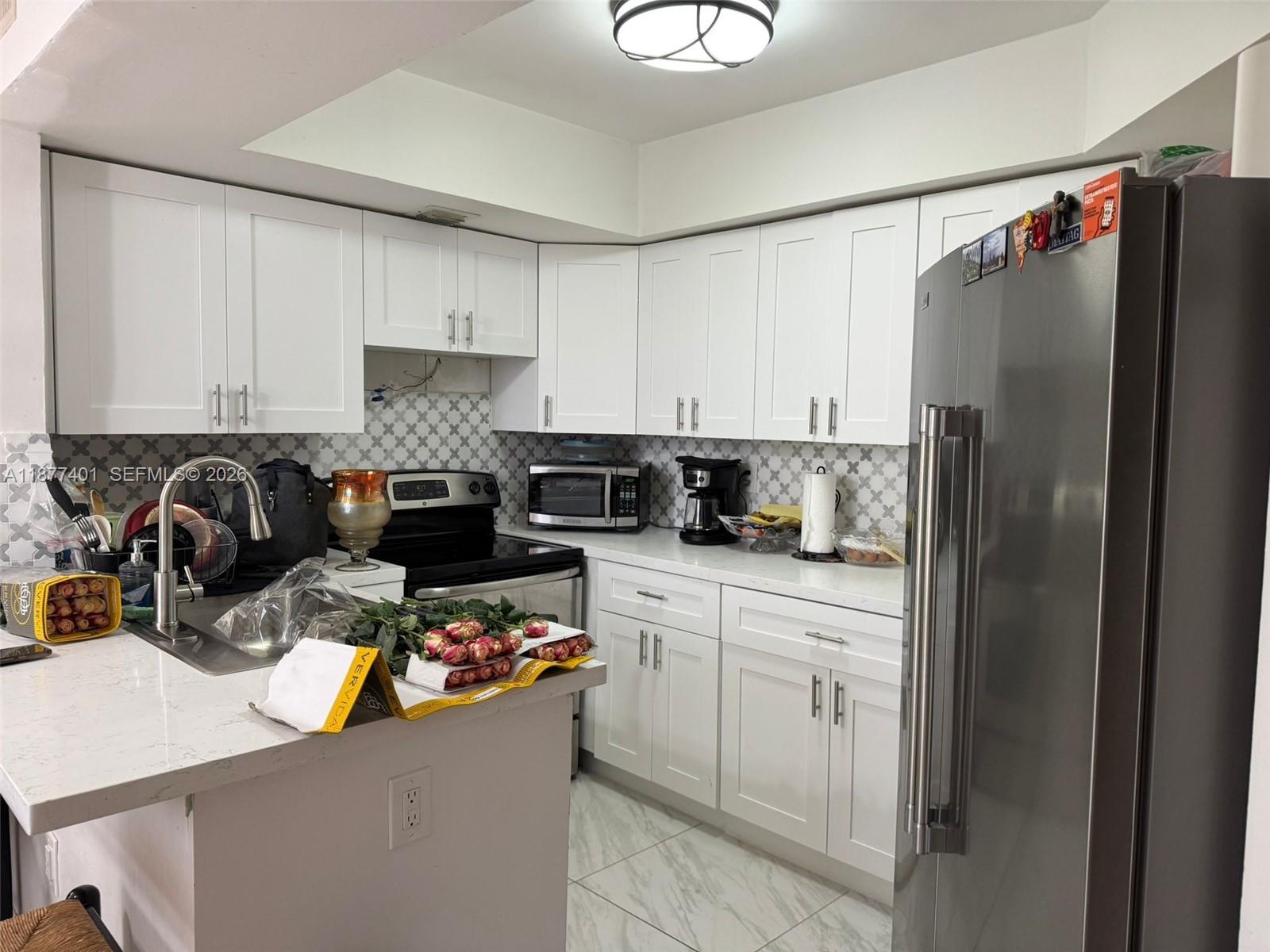 8205 Southwest 152nd Avenue, Unit F414 Miami, FL 33193 - Photo 2 of 13 a kitchen with a refrigerator and a stove top oven