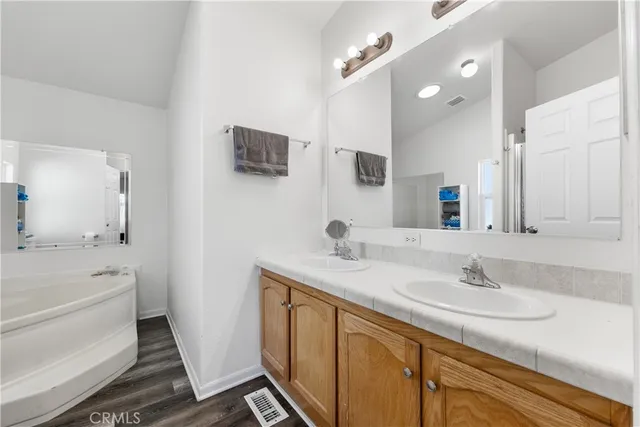 a bathroom with a sink double vanity granite tub shower and a mirror