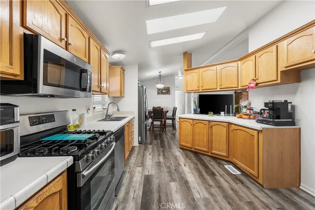 a kitchen with stainless steel appliances granite countertop a stove top oven a sink dishwasher and white cabinets with wooden floor