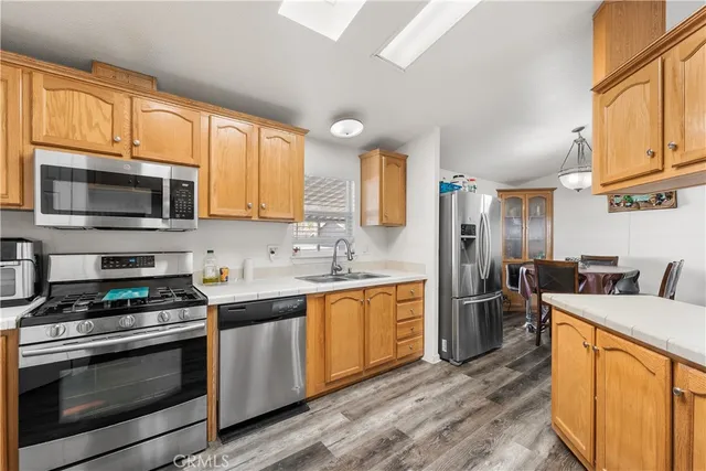 a kitchen with stainless steel appliances granite countertop a stove top oven a sink dishwasher a refrigerator and cabinets with wooden floor