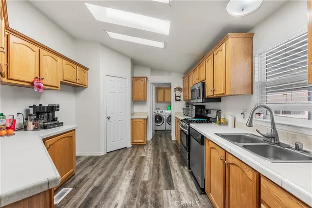 a kitchen with stainless steel appliances granite countertop a sink dishwasher stove and refrigerator with wooden floor