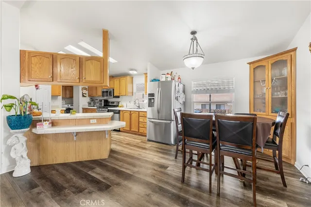 a living room with a dining table chairs wooden floor and kitchen view