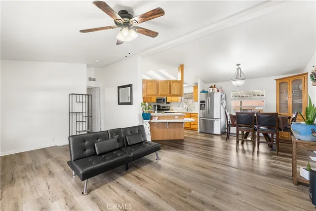 a living room with couches and kitchen view with wooden floor