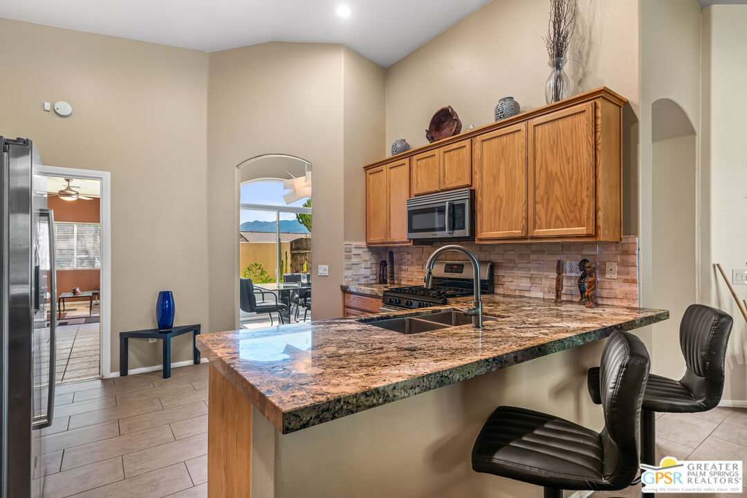67860 Ontina Road Cathedral City, CA 92234 - Photo 13 of 48 a kitchen with stainless steel appliances granite countertop a sink a stove counter space and cabinets