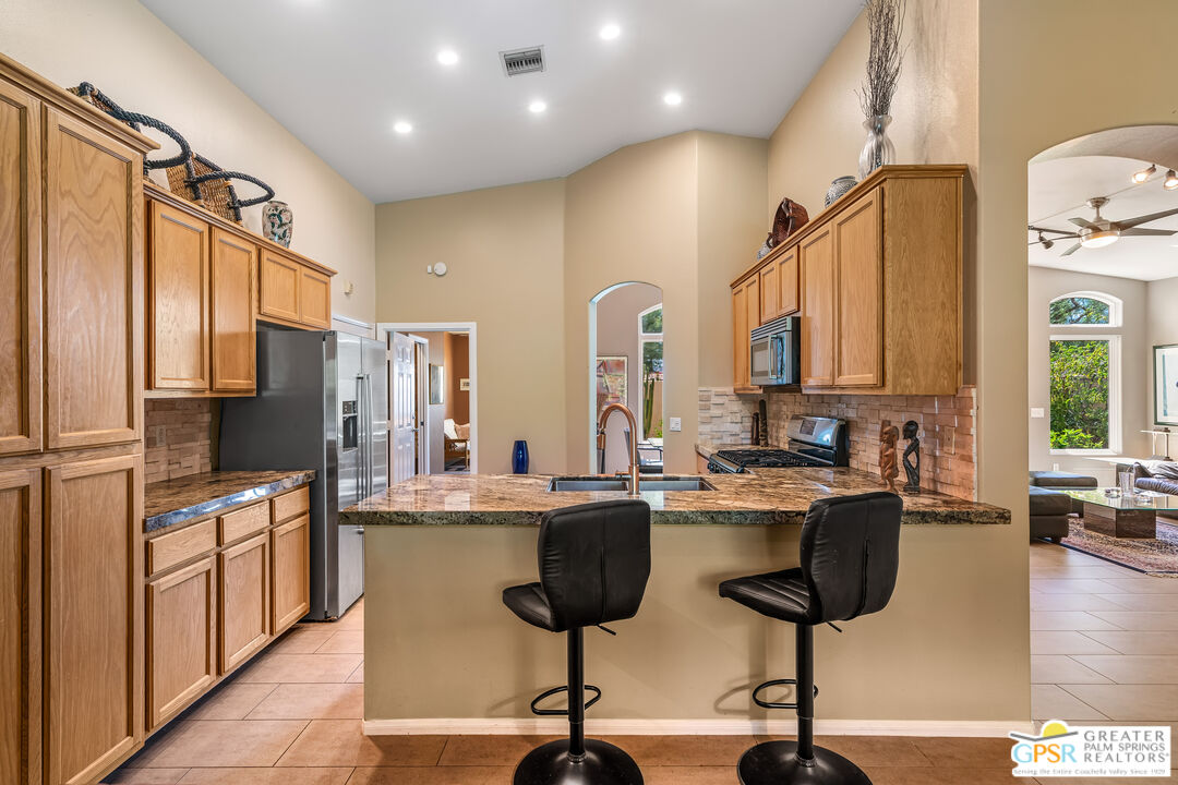 67860 Ontina Road Cathedral City, CA 92234 - Photo 14 of 48 a kitchen with stainless steel appliances granite countertop a refrigerator a stove and white cabinets with wooden floor