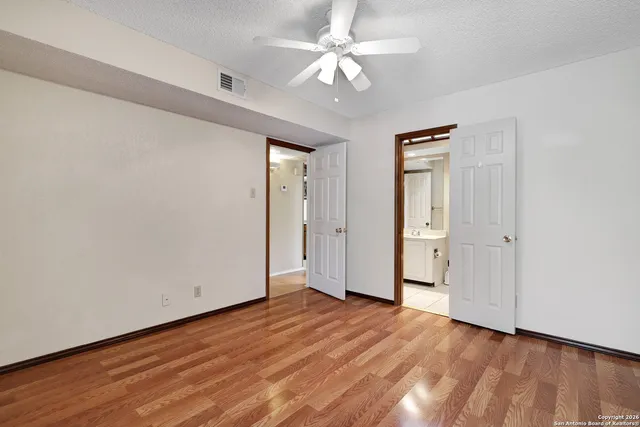 an empty room with wooden floor and ceiling fan