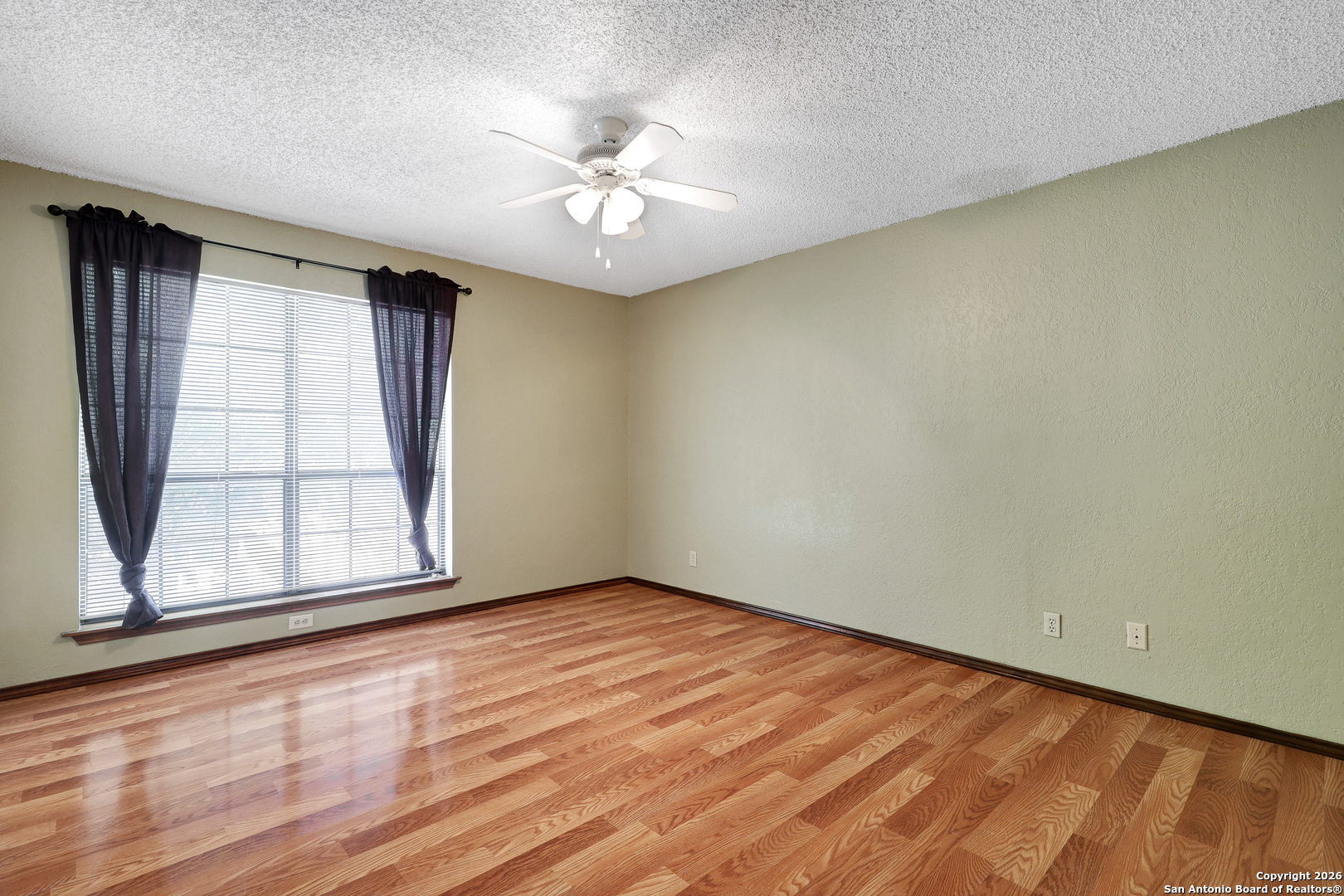 8633 Datapoint Drive, Unit 224 San Antonio, TX 78229 - Photo 18 of 27 an empty room with wooden floor chandelier fan and windows