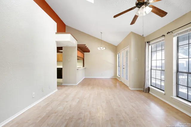 a view of empty room with wooden floor and fan
