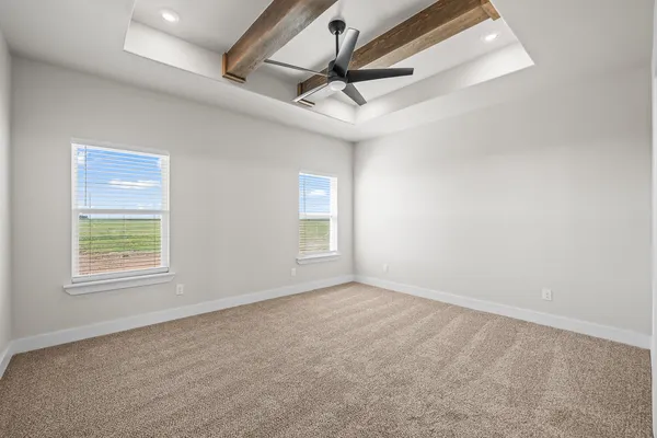 an empty room with a ceiling fan and windows