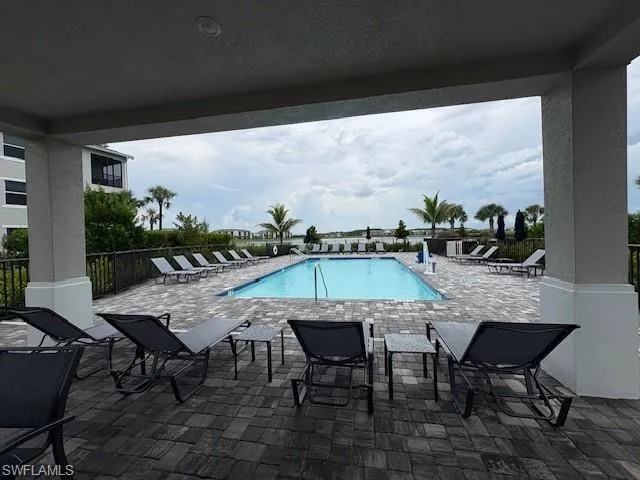 a dining hall with stainless steel appliances granite countertop a table chairs and a chandelier