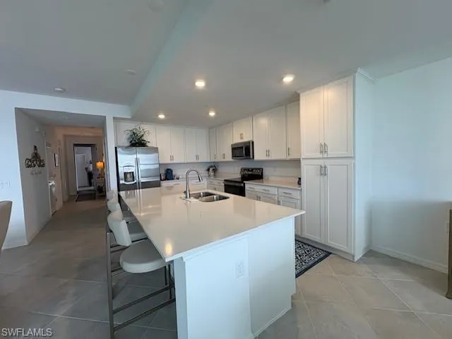 a large kitchen with kitchen island a sink a stove a refrigerator and white cabinets